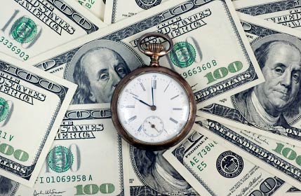 A stock photo of a clock on top of a pile of money.