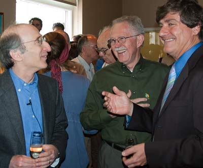 Three older white men laugh together at a party.