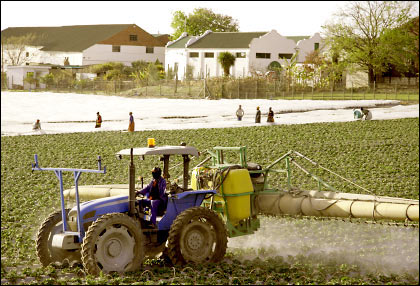 A tractor spraying pesticide near homes.