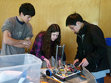 Three students work on a robot.
