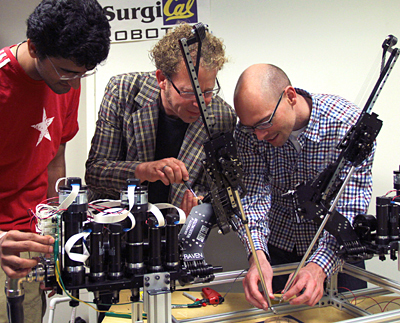 3 people in a lab working with robots.