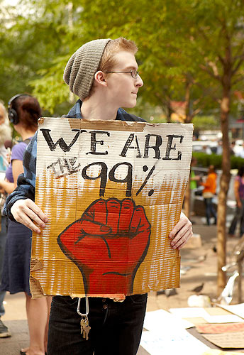a person holds up a sign that reads "We are the 99 percent."