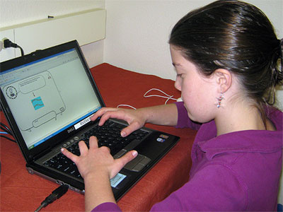 A girl plays an educational game on a laptop.