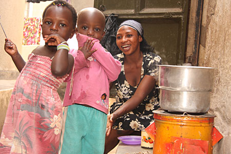 Two small children and their mother next to a cookstove.