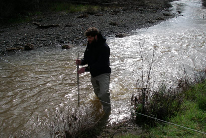 Grantham stands knee deep in a fast moving stream.