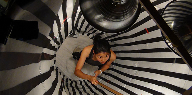 Image of woman standing in black and white cylinder, taken from overhead