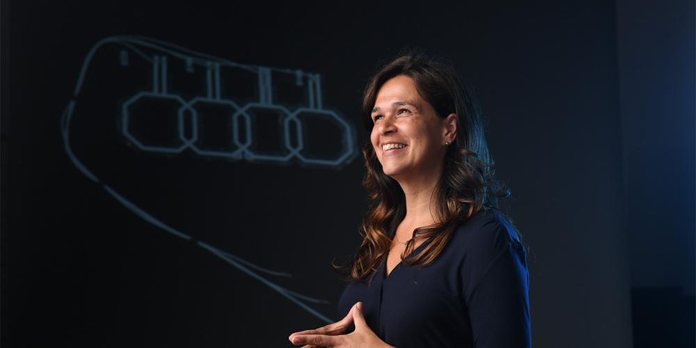 Ana Claudia Arias standing in front of a projected graphic of her research