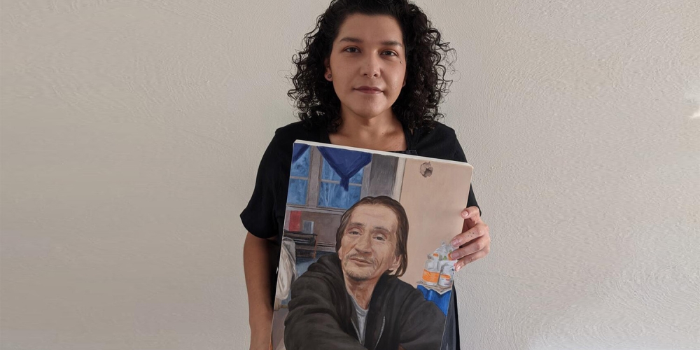 Luanne Redeye holding a portrait of a man in a black sweatshirt