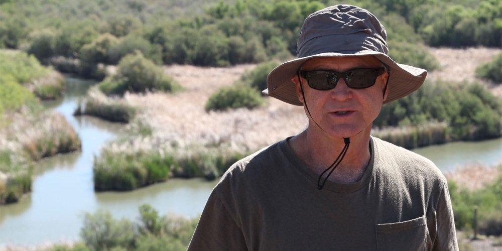Mathias Kondolf wearing hat and holding notebook at the Bill Williams River in Arizona