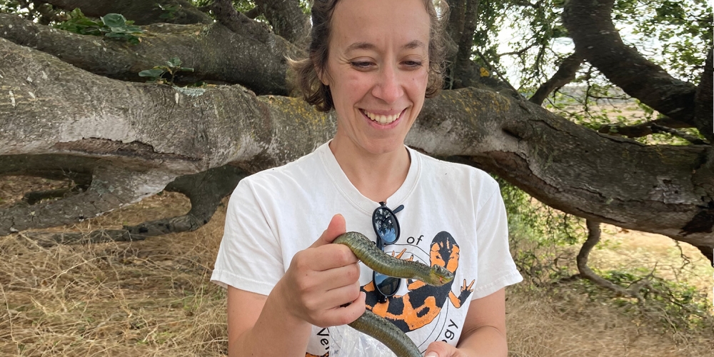 Rebecca Tarvin in the field holding a snake