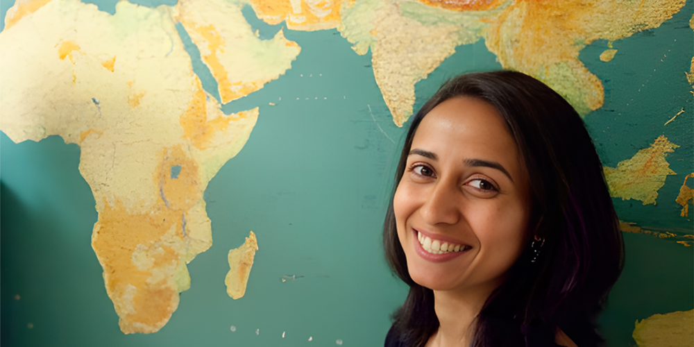 Priya Moorjani standing in front of map of the world