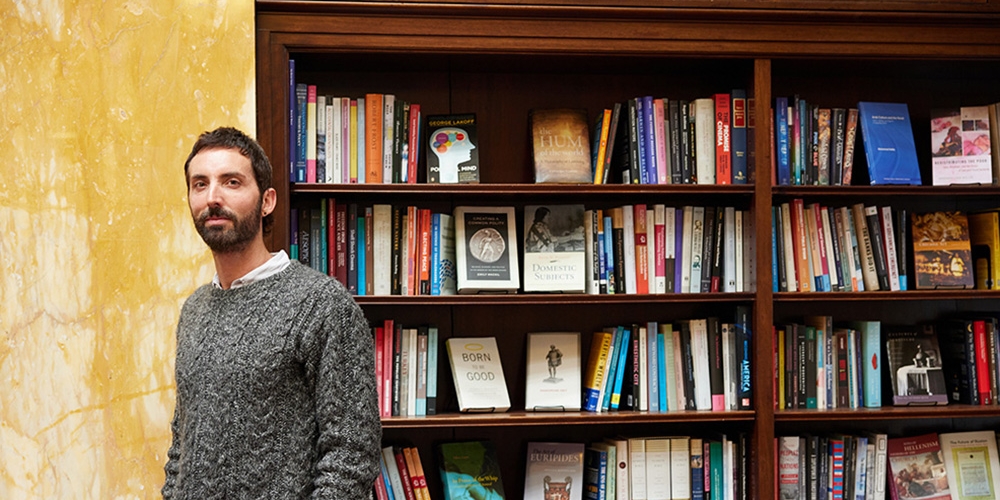 Damon Young standing in front of book shelves full of reading material