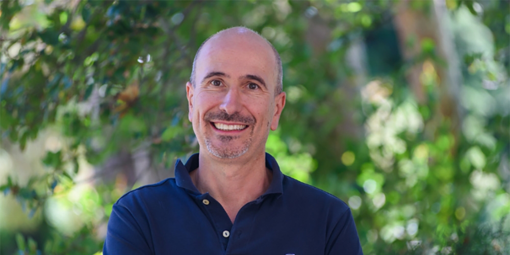 Paolo D'Odorico wearing a blue shirt, with unfocused greenery in background