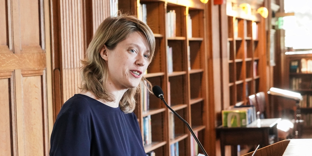 Lenssen standing at lecturn, delivering speech at a library event