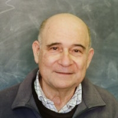 photographed in front of the blackboard in his office