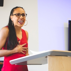 Woman wearing a red jumpsuit while presenting