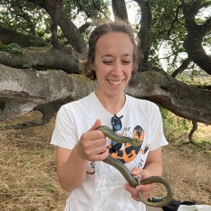 Rebecca Tarvin in the field holding a snake