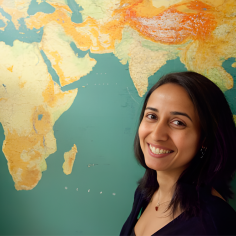 Priya Moorjani standing in front of map of the world