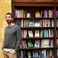 Damon Young standing in front of book shelves full of reading material