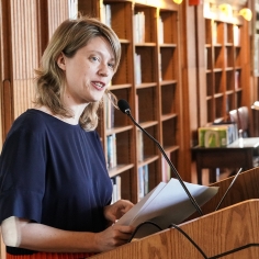 Lenssen standing at lecturn, delivering speech at a library event