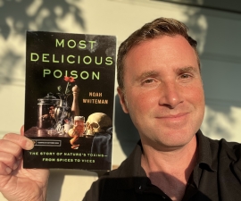 Photo of Noah Whiteman holding a copy of his book MOST DELICIOUS POISON -- The Story of Nature's Toxins -- from Spices to Vices