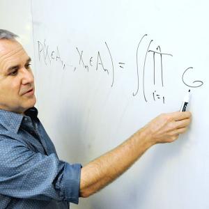 Man pointing to writing on a white board.