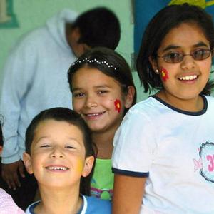 Children with face-paintings looking in the direction of the camera and smiling.