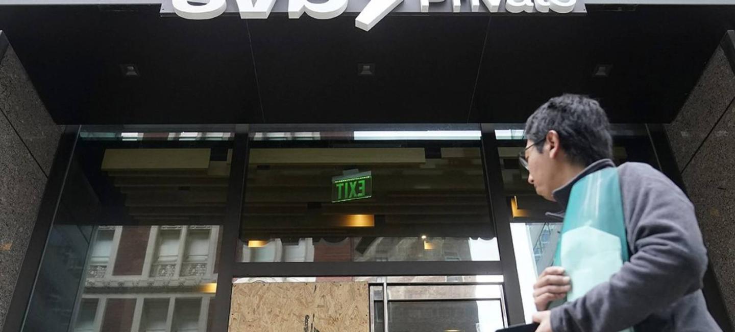 Someone walks by the SVB bank with one door boarded up (Credit: AP Photo/Jeff Chiu)