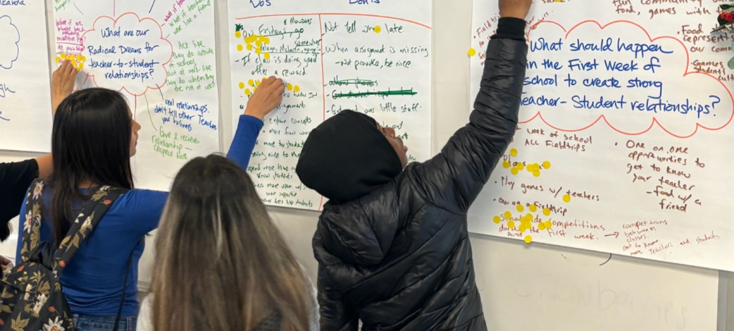 Students point toward poster paper on the wall during an exercise about the ways to better understand chronic absenteeism among students.