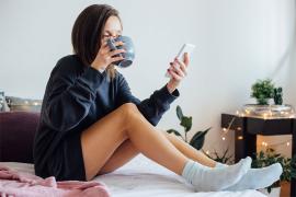 Woman sitting on bed looking at phone