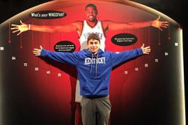 A boy stretches his arms out while standing in front of a life-size photo of Kevin Durant's wingspan