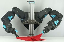 Two robot arms hold a red towel