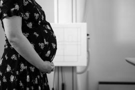 A photo of a pregnant woman in a black dress holding her belly