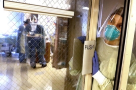 A nurse waits in an open doorway in a hospital ICU