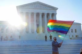 a man waves a rainbow flag in front of the supreme court building