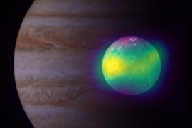 a green and yellow Io shown in front of Jupiter