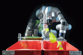 A photo of a grey and blue robotic arm against a black background. The arm is blurry, and appears to be in the process of moving a small green squirtbottle from one red bin to another red bin.
