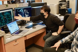 researchers wearing protective masks looking at computer screens