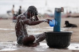 On a day of scorching temperatures, a man in India sits and drenches himself in water from a public fountain