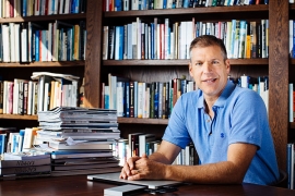 A photo of Daniel Kammen at a desk in front of a large bookshelf.