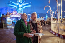 Older couple having fun together at a fairground carnival.