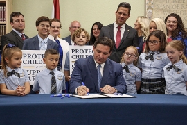 Florida Governor Ron DeSantis signs the controversial "don't say gay" bill, surrounded b school childrenand parents