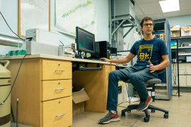 A photo of a student wearing a "Berkelium" t-shirt while sitting at a computer