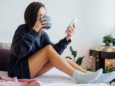 Woman sitting on bed looking at phone