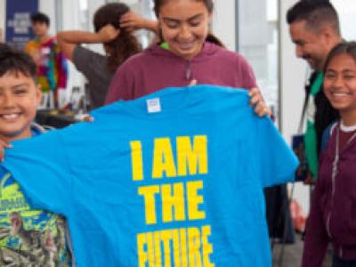 students hold blue t-shirt with yellow lettering reading "I am the future"