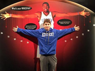 A boy stretches his arms out while standing in front of a life-size photo of Kevin Durant's wingspan