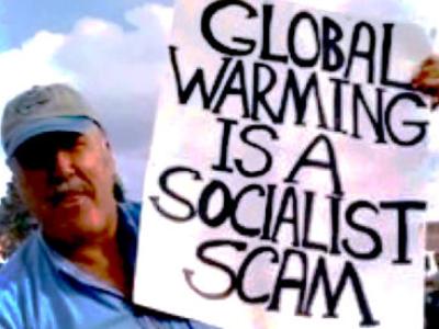 Man holding sign reading "Global Warming is a Socialist Scam"