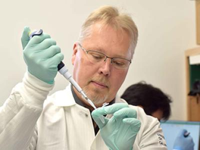Anders Naar holds a pipette and test tub in a lab