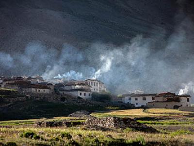 Photo shows houses on a hillside with smoke emerging from smokestacks