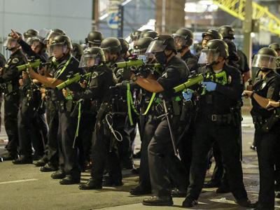 A line of police officers in riot gear point weapons containing rubber bullets at protesters in Los Angeles following the death of George Floyd, a black man who was killed in police custody on May 25.